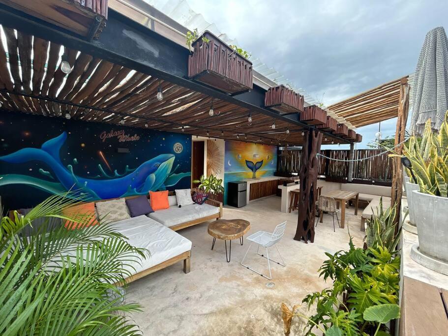 eine Terrasse mit einem Sofa und einem Wandbild in der Unterkunft BULUC LUCH PH para grupos con Roof top y alberca privada in Tulum