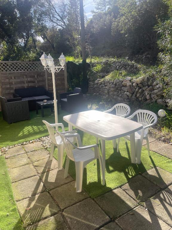- une table et des chaises blanches dans la cour dans l'établissement Charmant logement avec jardin privatif à la campagne, au Beausset