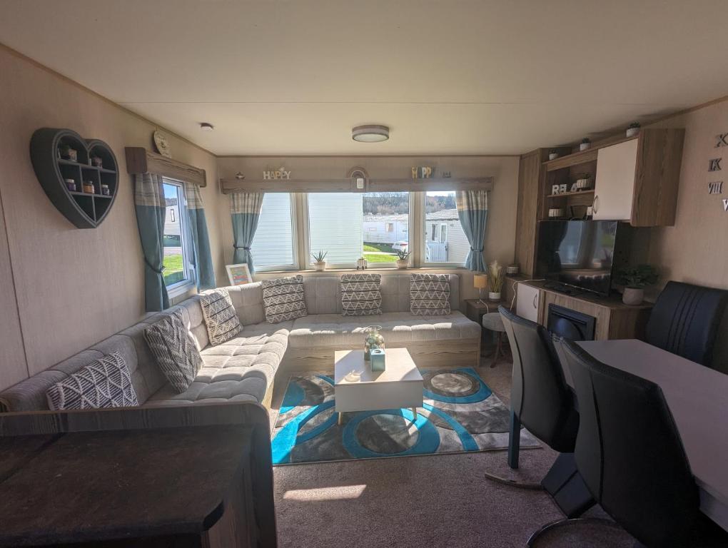 a living room with a couch and a table at Caravan sleeps 8 at Littlesea, Weymouth in Wyke Regis