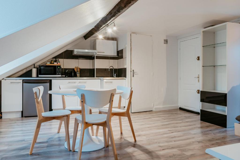 une cuisine avec des armoires blanches et une table et des chaises dans l'établissement Octave 29, au Havre