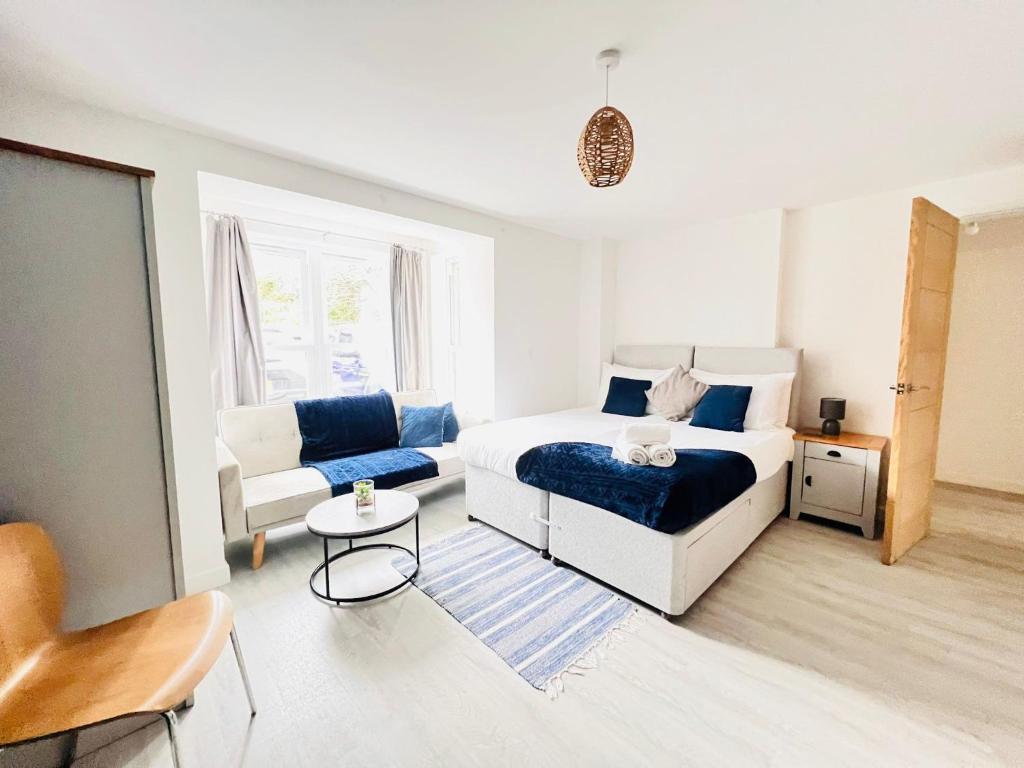 een witte slaapkamer met een bed en een bank bij Stylish Cambridge Apartment with Garden in Cambridge