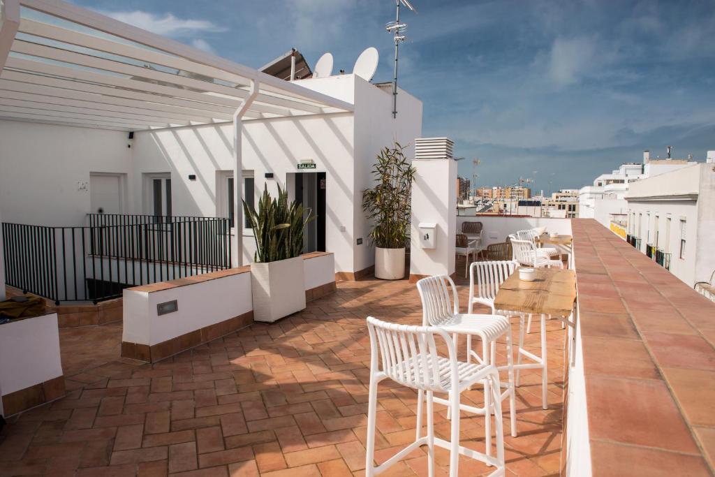 patio z białymi krzesłami i stołami na dachu w obiekcie Torre Solana 41 w Kadyksie