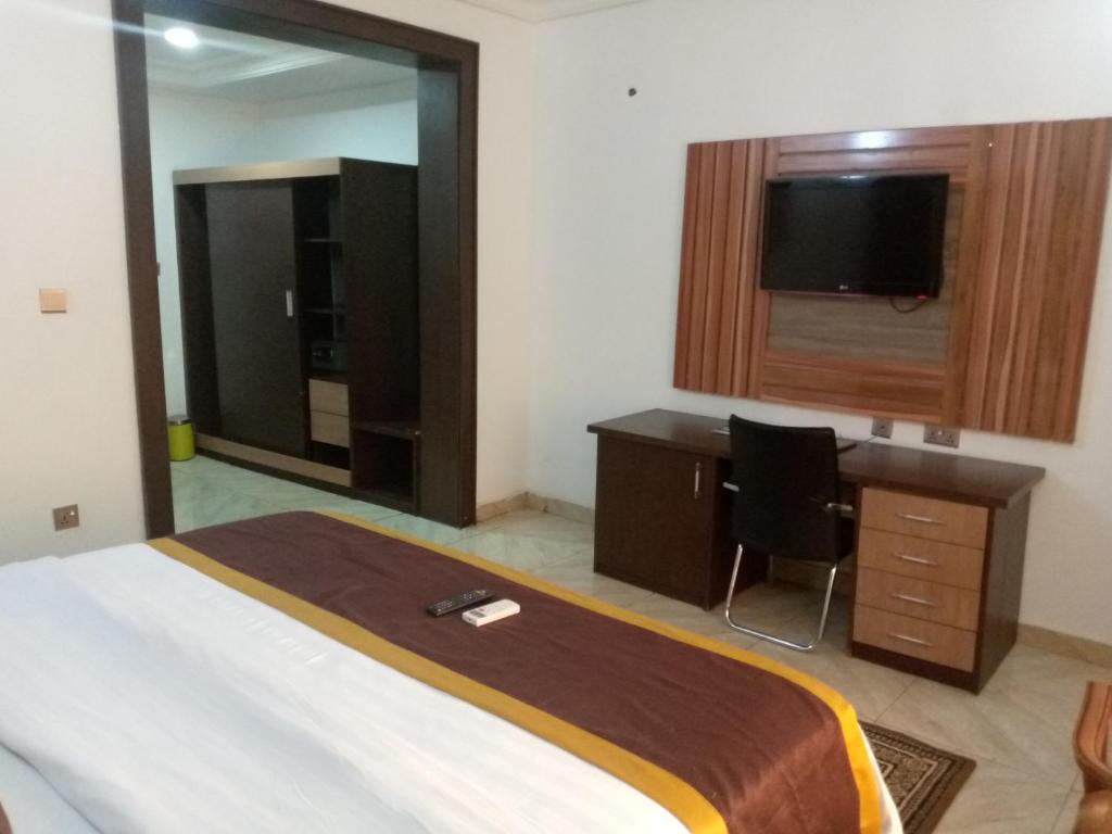 Dormitorio con cama, escritorio y TV en Immaculate Diamond Hotel & Apartments, en Abuja