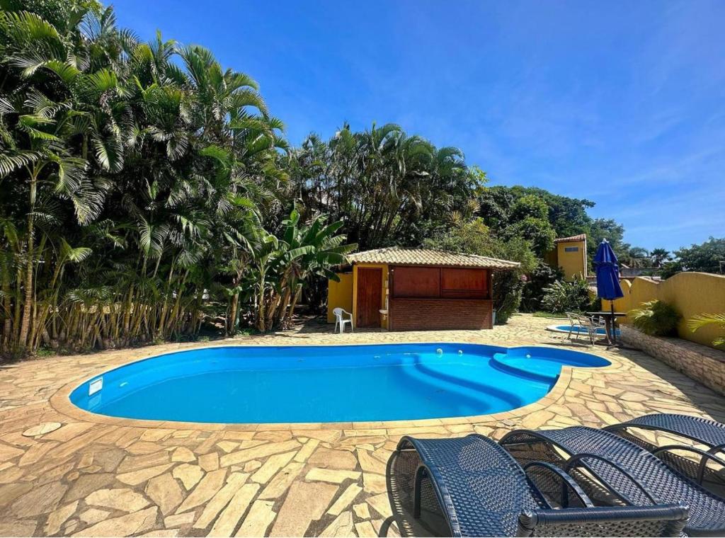 a swimming pool in a yard with chairs around it at Pousada Bosque dos Papagaios in Búzios