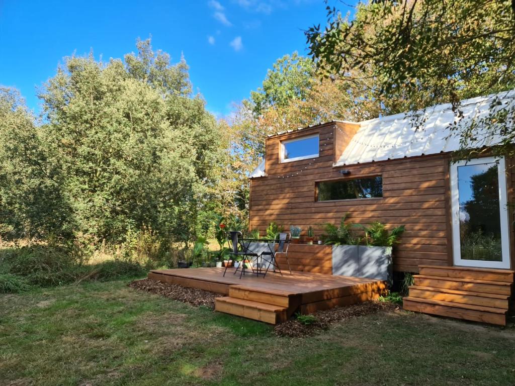 uma cabina de madeira com um deque no pátio em Tiny House Les nuits du Verger em Couëron