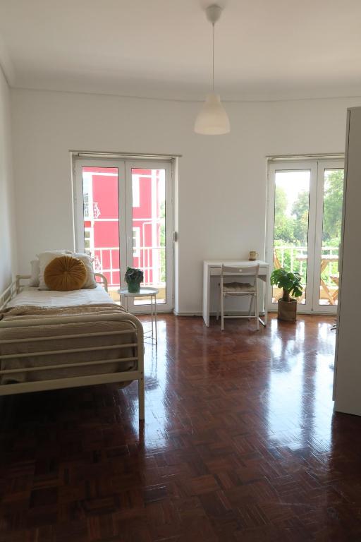 a bedroom with a bed and wooden floors and windows at Alvalade SkyView CoLiving in Lisbon