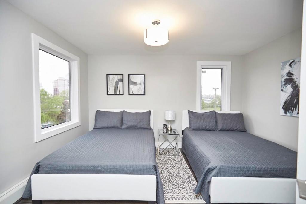 two beds in a white room with two windows at Clifton Hill Hideaway 4A - Two Bedroom Condo in Niagara Falls