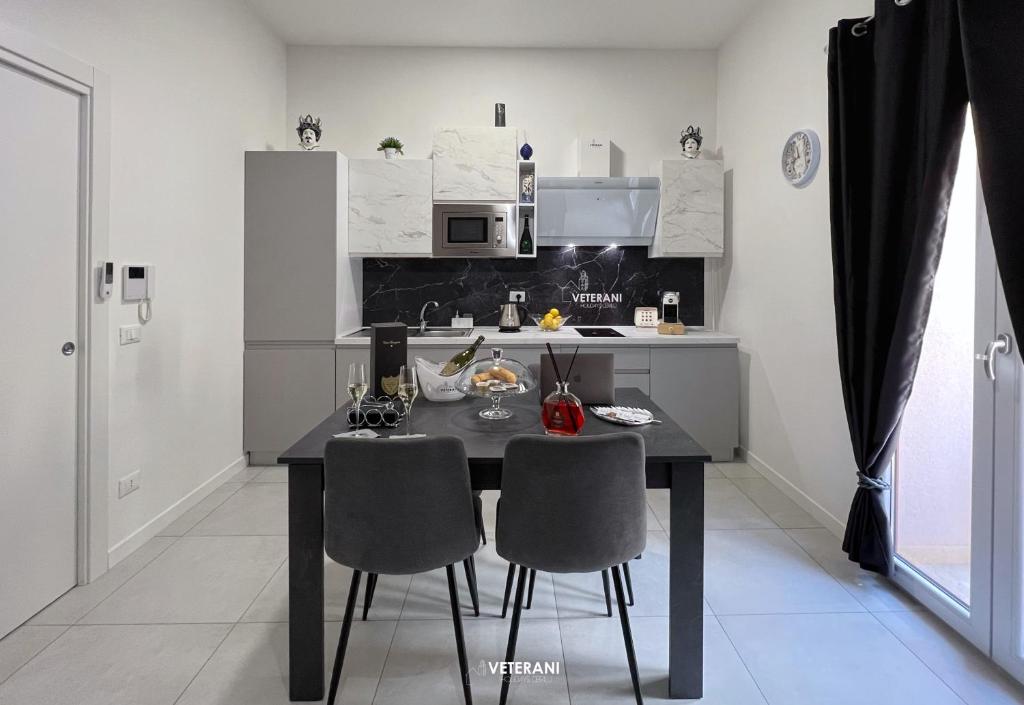 uma cozinha com uma mesa preta e duas cadeiras em Veterani Holidays Cefalù em Cefalù