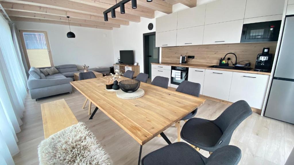 cocina y sala de estar con mesa de madera y sillas en Chalet MIA, en Mýto pod Ďumbierom