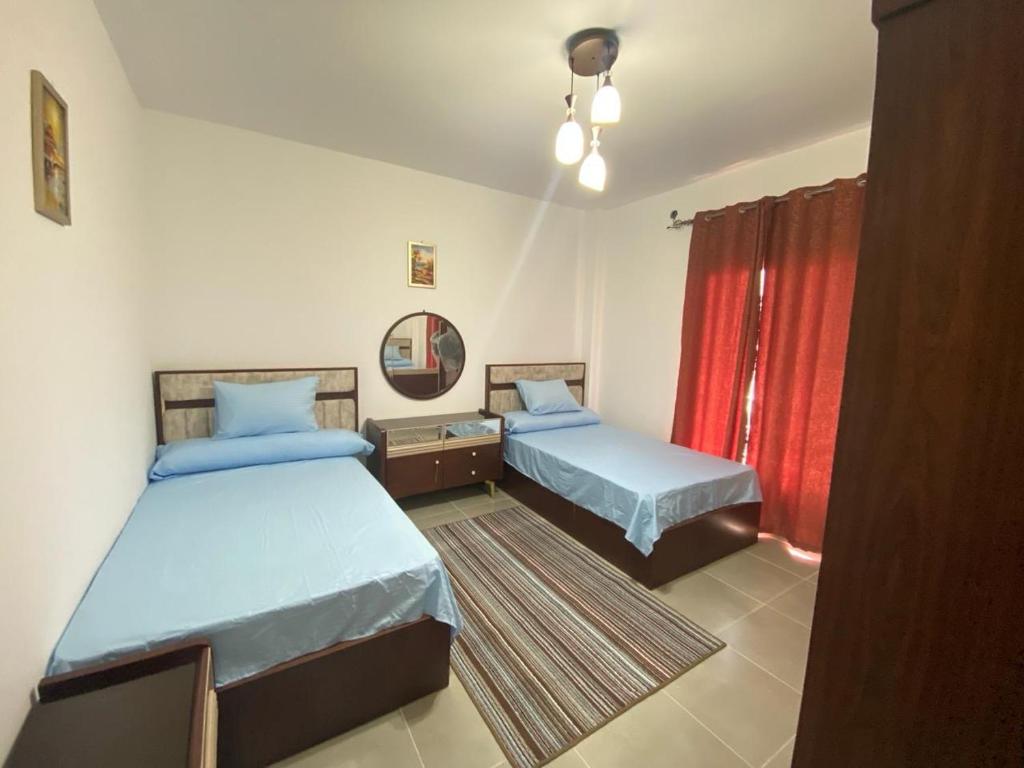 a bedroom with two beds and a red curtain at قريه امواج بالساحل الشمالي شاليه دوبلكس فاخر in Sīdī ‘Abd ar Raḩmān