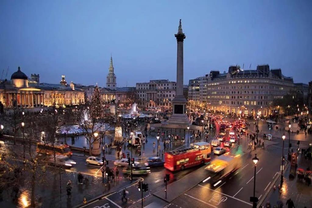 a busy city street with traffic at night with a monument at 2 bed arty flat at Trafalgar Square in London