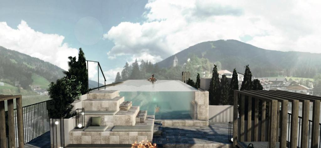 聖坎迪多的住宿－Loewe Dolomites，站在游泳池顶上的男人