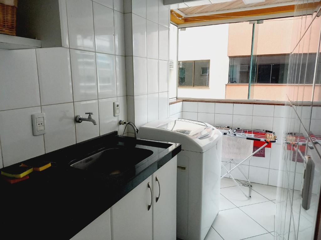uma cozinha com um lavatório e uma máquina de lavar roupa em Excelente apartamento em Itapema