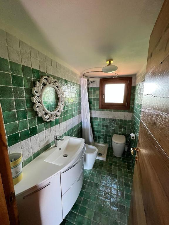 Un baño con lavabo, inodoro y espejo. en Coralli House, en Casagliana