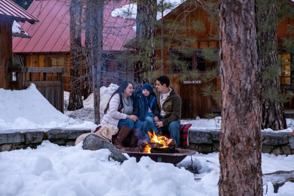 a group of people sitting around a fire in the snow at Sleeping Lady Mountain Resort in Leavenworth