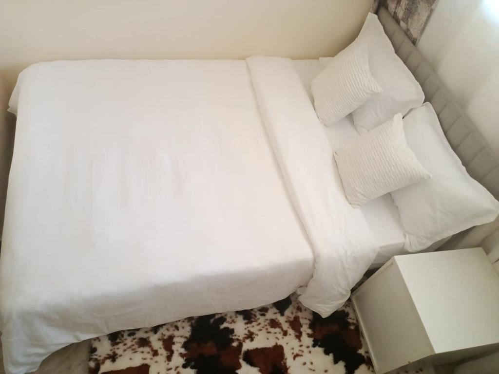 a bed with white sheets and pillows in a room at The Pearl Cage Gigiri-Near US Embassy in Nairobi