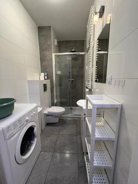 a bathroom with a washing machine and a toilet at Abra V Apartament in Poznań