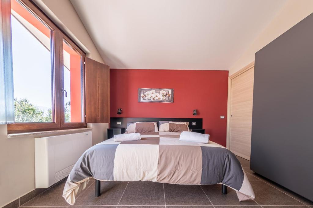 - une chambre avec un grand lit et un mur rouge dans l'établissement Sanbarto la Casa del Borgo, 