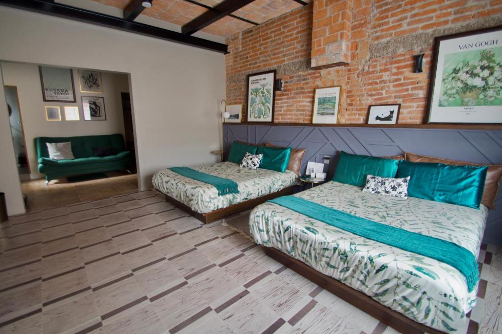 a bedroom with two beds and a brick wall at Hotel Boutique Santa Elena in San Luis Potosí