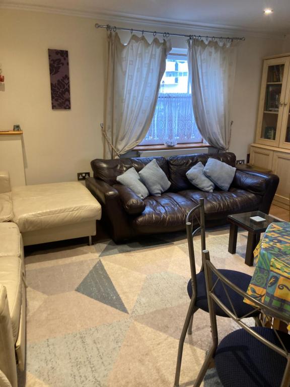 een woonkamer met een leren bank en een raam bij Broxbourne Two-Bedroom Apartment Close To Amenities in Hoddesdon