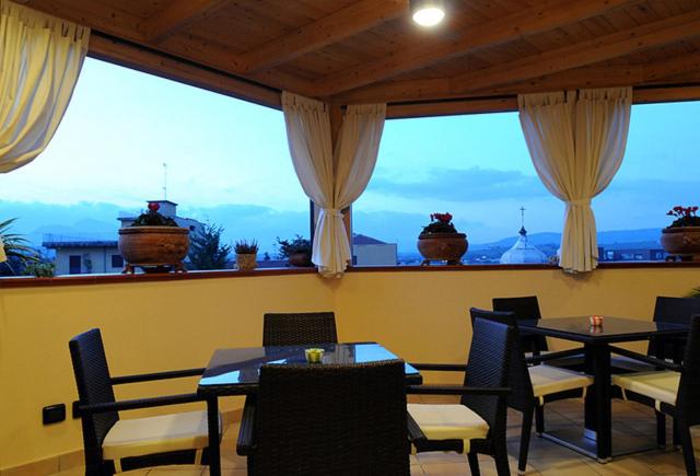 un restaurante con mesas y sillas y una gran ventana en B&B Domus Traiani Benevento, en Benevento