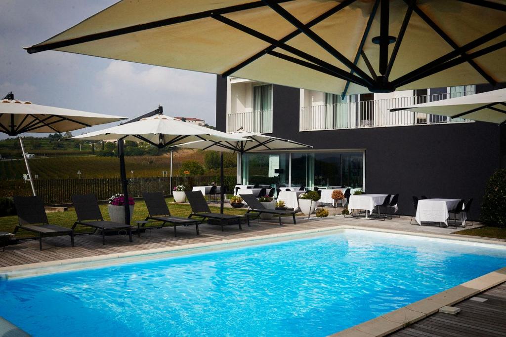 a swimming pool with chairs and umbrellas next to a building at House Iaquin in Dobrovo