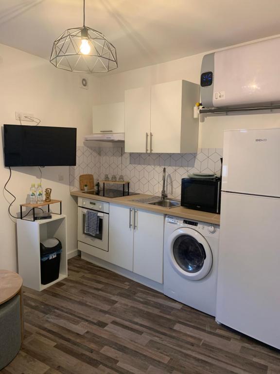 uma cozinha com uma máquina de lavar roupa e um frigorífico em Studio lumineux et équipé em Villemomble