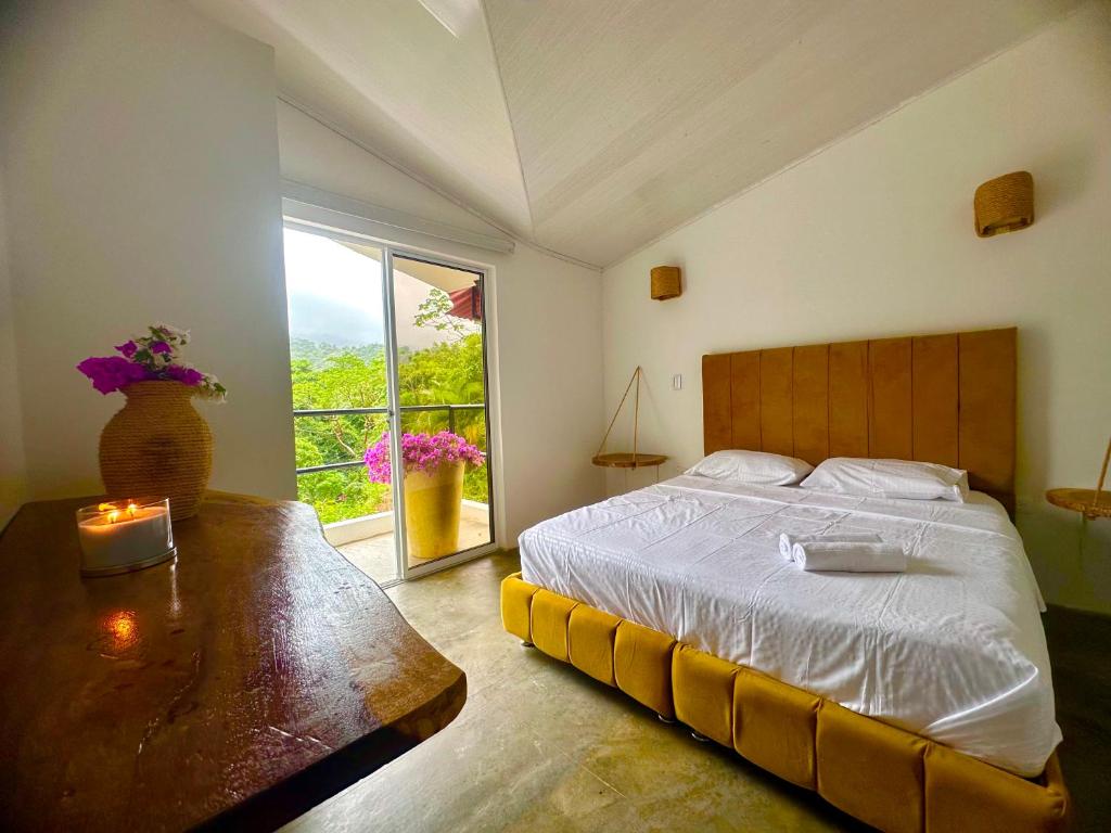 Schlafzimmer mit einem Bett, einem Tisch und einem Fenster in der Unterkunft Tayrona Angel Lodge in El Zaino