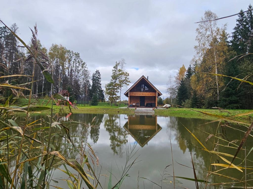 a small cabin is reflected in a pond at Atpūtas māja Kaktiņi Rīga in Ikšķile