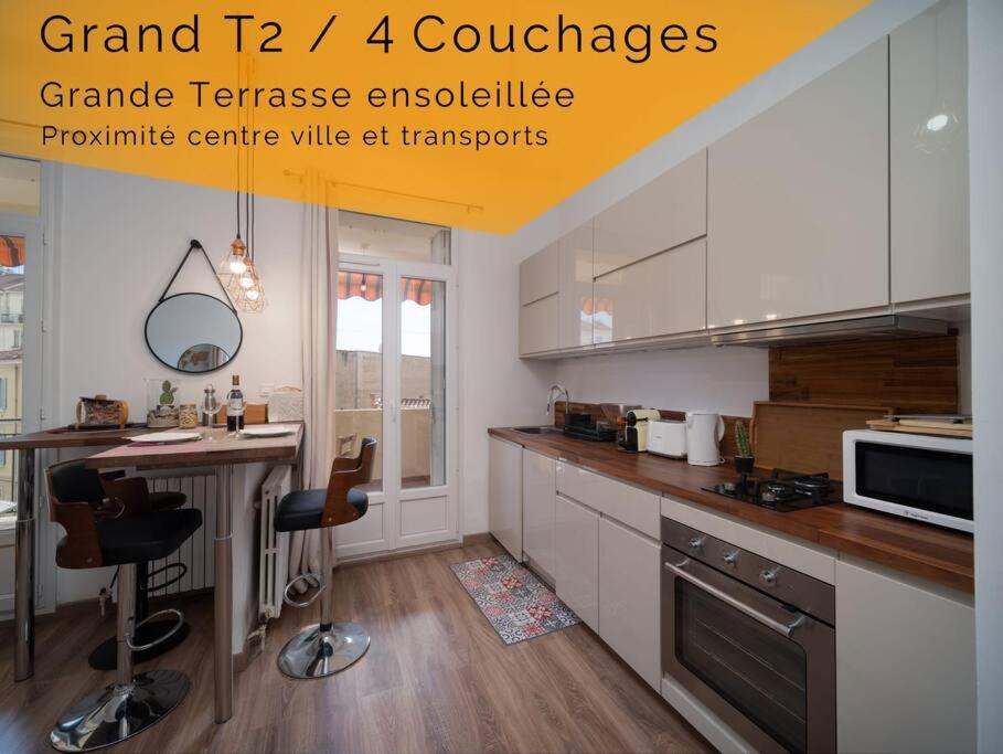 une cuisine avec des placards blancs et un comptoir avec des chaises dans l'établissement Appartement tout équipé avec terrasse au cœur de Marseille, à Marseille