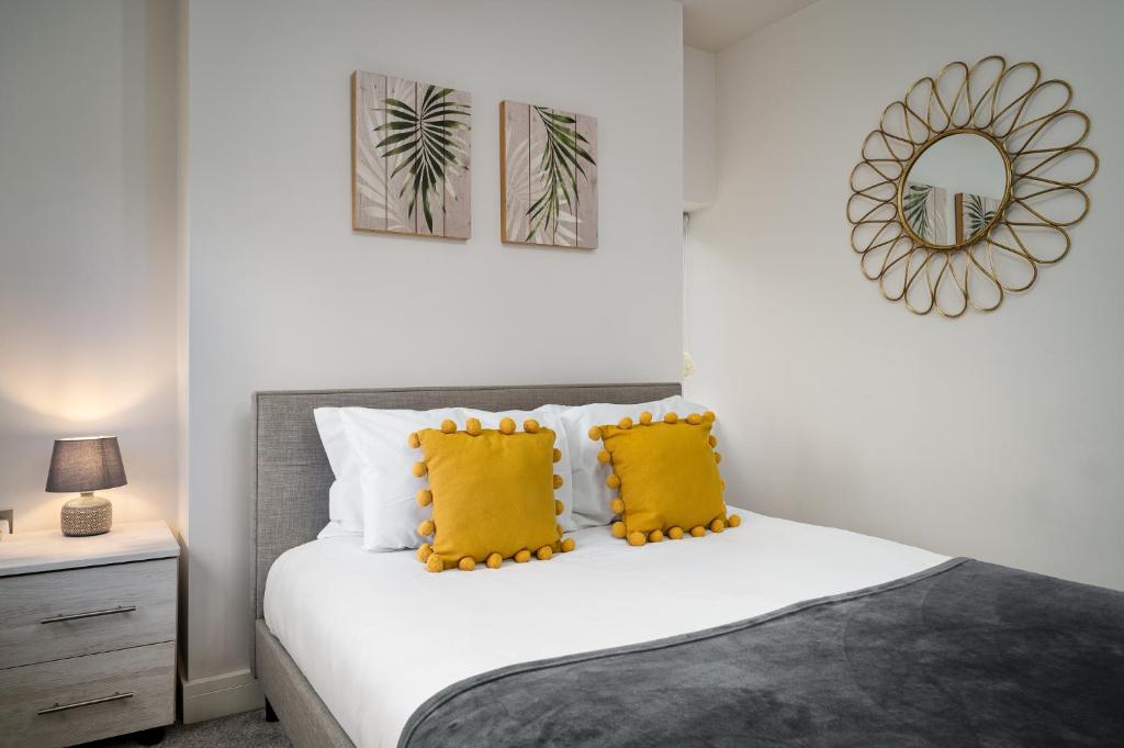 1 dormitorio con cama con almohadas amarillas y espejo en Coppergate Mews Apartment Doncaster 3, en Doncaster