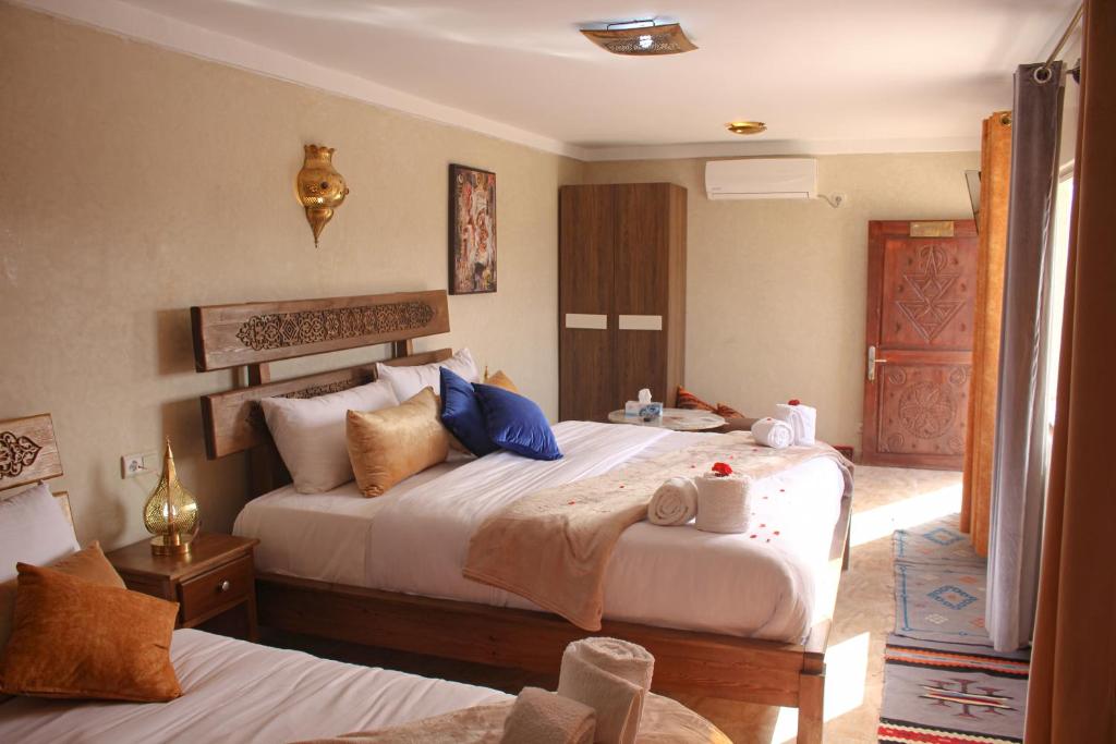 a hotel room with two beds and a door at Maison D'hôtes IMINIGRAN & Spa in Ouarzazate