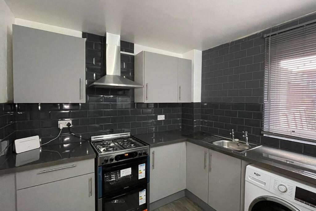 uma cozinha com armários brancos e um forno com placa de fogão em M6 Jct 10, 2 Bed House Wolverhampton-Walsall em Willenhall