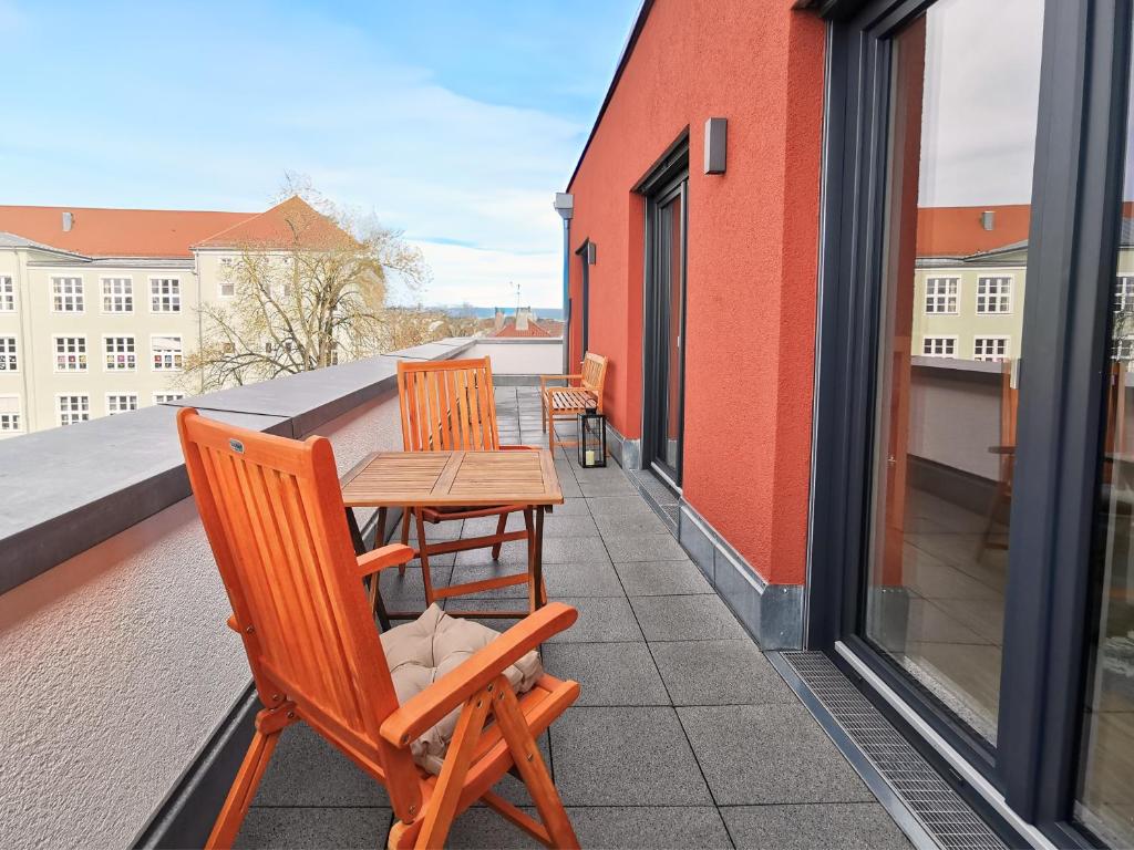 d'une terrasse avec 2 chaises et une table sur un balcon. dans l'établissement Fynbos City Penthouse, Dachterrasse, Design-Küche, Parkplatz, à Straubing