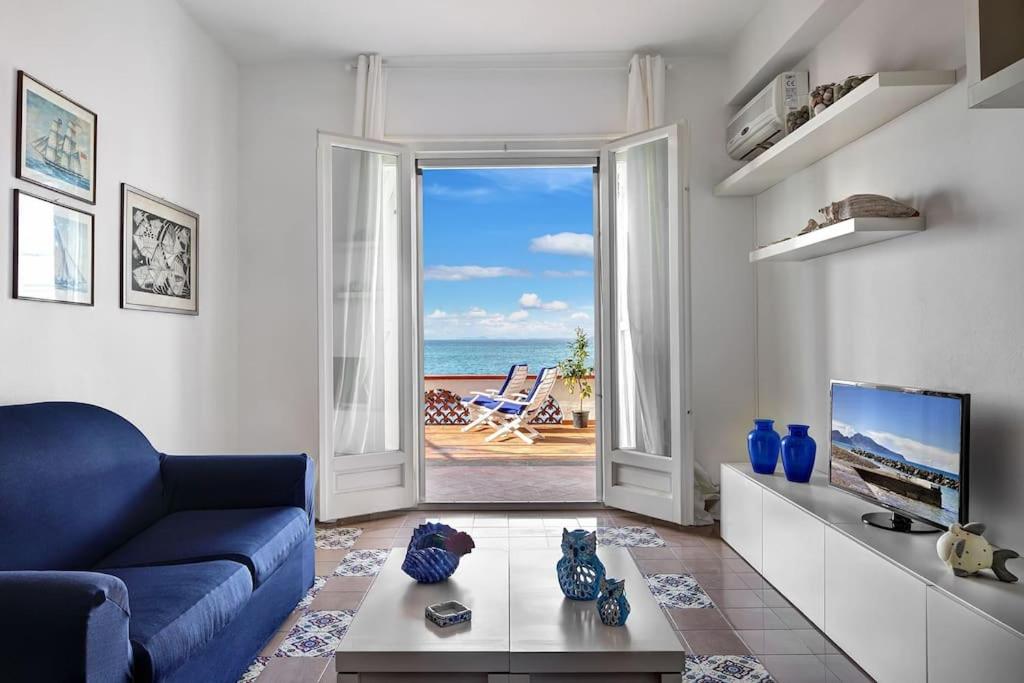 a living room with a blue couch and a view of the ocean at Raffaela's House - (San Montano) in Massa Lubrense