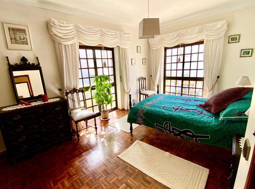a bedroom with a green bed and two windows at Spray B&B Sitio in Nazare, European style in Nazaré