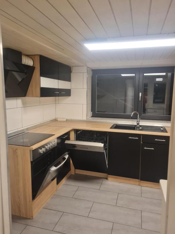 eine Küche mit schwarzen Geräten und einem Waschbecken in der Unterkunft Zimmer zu vermieten in Gundelsheim