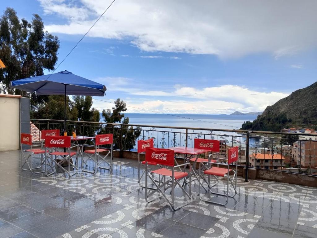 een patio met rode stoelen en tafels en een parasol bij Villa Bella Copacabana in Copacabana