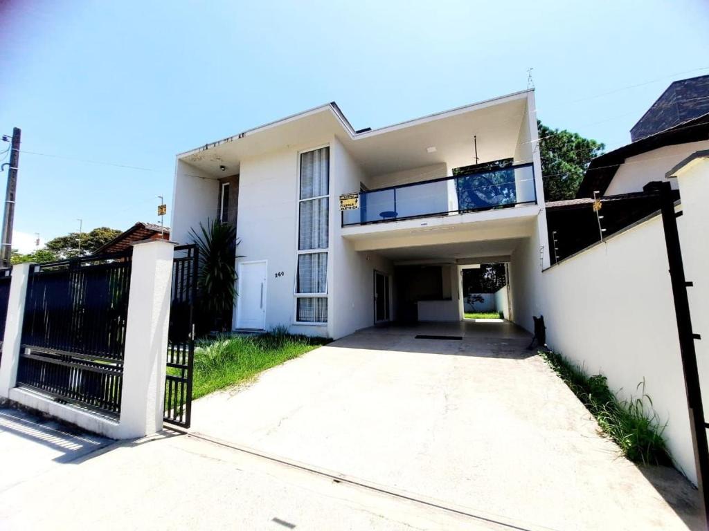 une maison blanche avec un portail et une allée. dans l'établissement Casa de 2 pisos a 110m da praia em Piçarras SAP260, à Balneário Piçarras