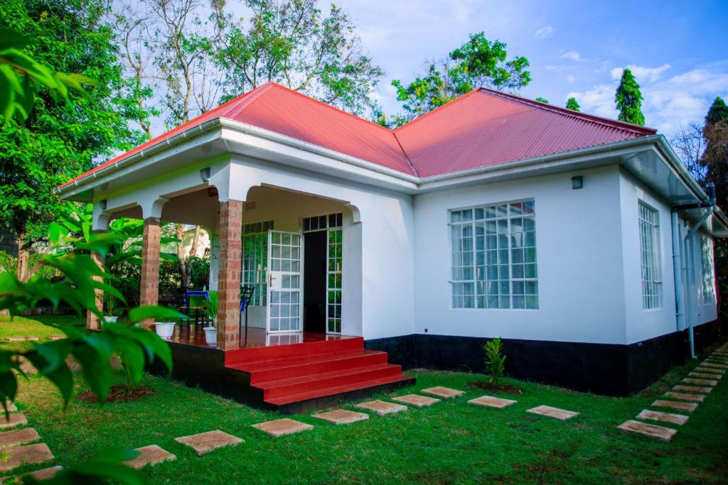 una pequeña casa blanca con techo rojo en Royal Homestay, en Moshi