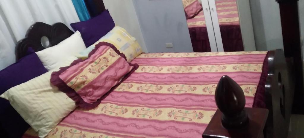 uma cama com um cobertor e almofadas em Casa familiar em Batey La Altagracia