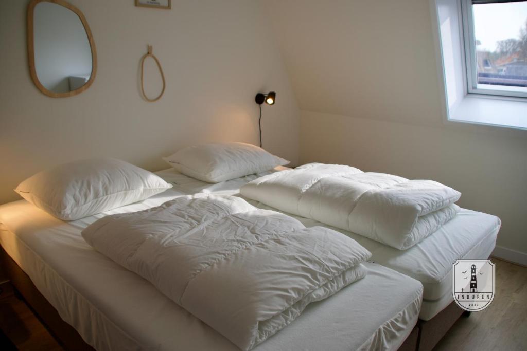 two white pillows on a bed in a room at InBuren in Buren