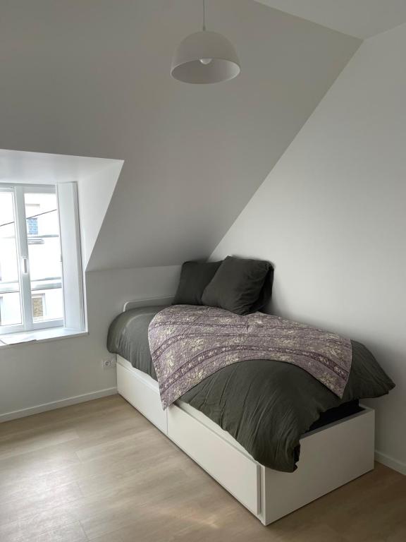 un lit dans une chambre blanche avec une fenêtre dans l'établissement Studio Rive Gauche, à Dinan