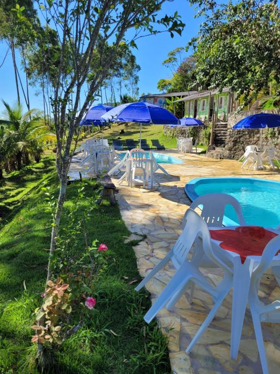 un tavolo e sedie accanto a una piscina con ombrelloni di Refugio de Itamambuca a Ubatuba