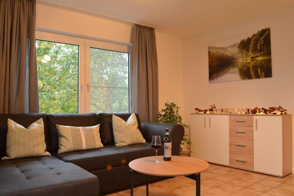 ein Wohnzimmer mit einem schwarzen Sofa und einem Tisch in der Unterkunft Ruhige Ferienwohnung im Grünen in Arnsberg