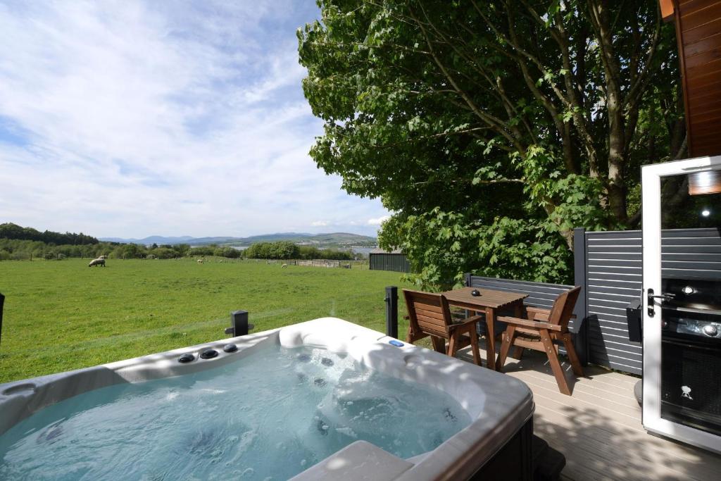 a hot tub on a deck with a table and chairs at Lomond View in Langbank