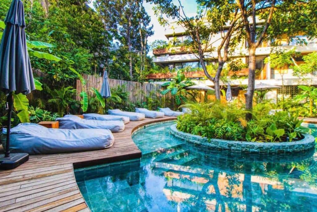 a backyard with a swimming pool and an umbrella at 5 Star NEW Luxury Condo with Cenote and Infinity Pool in Tulum