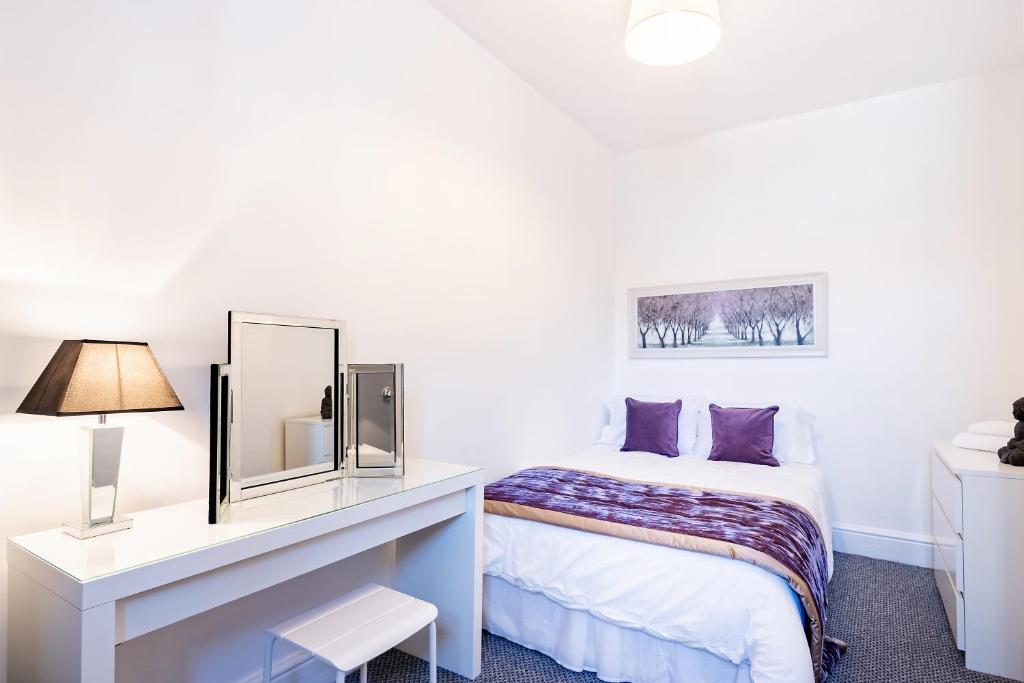 a white bedroom with a bed and a mirror at The Urban Apartment in Doncaster