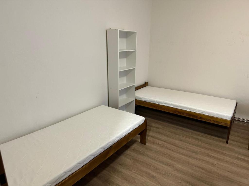 twee bedden in een kamer met witte muren en houten vloeren bij Breznicka 91 in Příbram
