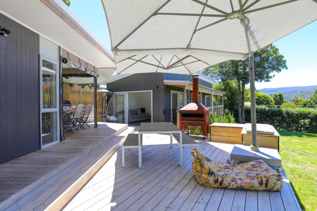 an outdoor deck with an umbrella and a grill at Kereru Rest in Rotorua